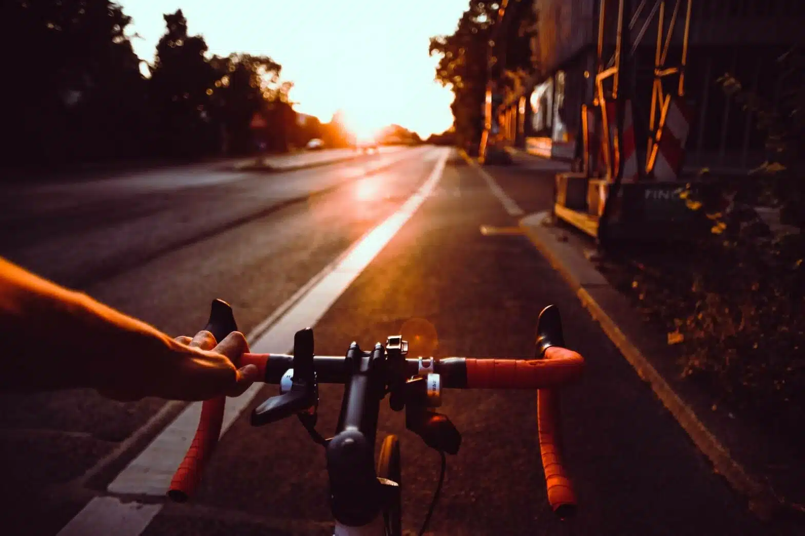kolarz jadący ulicą przy zachodzie słońca